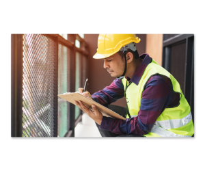 Construction worker kneeling while taking notes